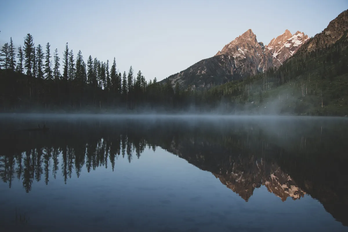 String Lake at dawn, with the Teton peaks reflected in still water.